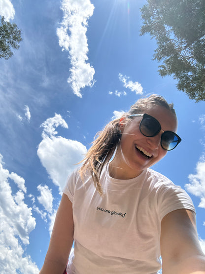 woman wearing white affirmation t-shirt you are glowing smiling outdoor sky lifestyle confidence