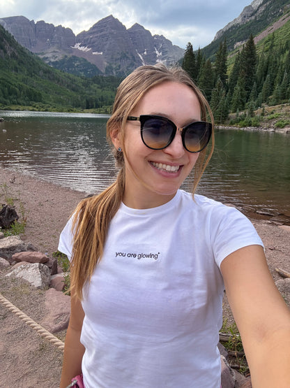 woman wearing white affirmation t-shirt you are glowing embroidered outdoor mountain lifestyle