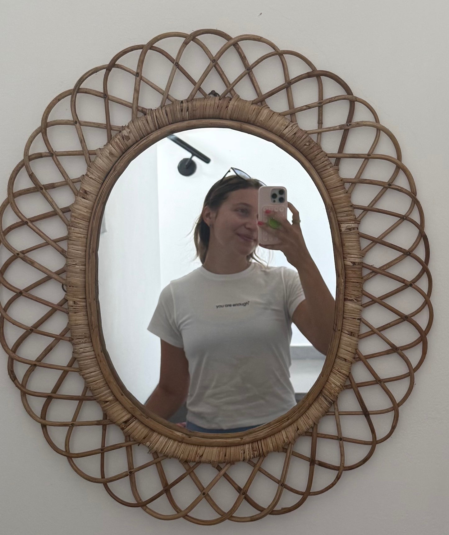 Person taking a mirror selfie with a decorative rattan-framed mirror wearing mirror moments you are enough tee