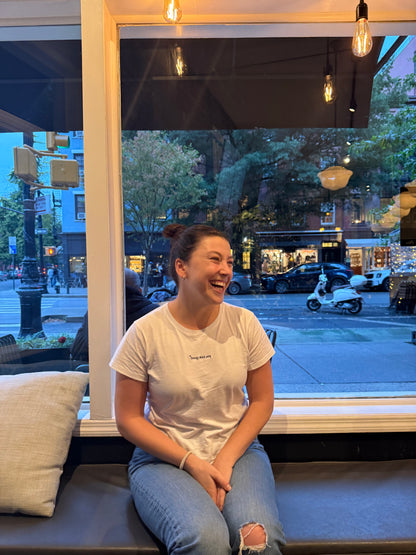 girl wearing white affirmation t-shirt you look good jeans smiling cafe city window lifestyle